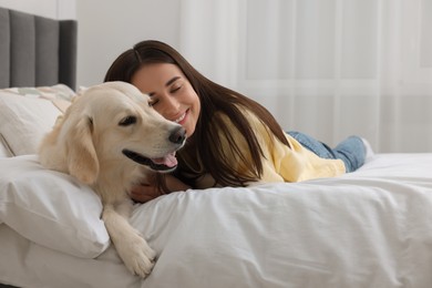 Happy woman with cute Labrador Retriever dog on bed at home. Adorable pet