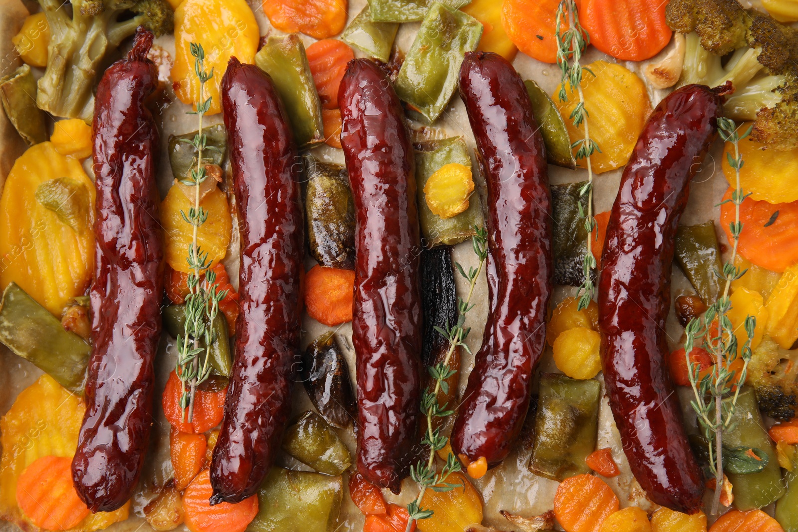 Photo of Delicious smoked sausages and baked vegetables, top view