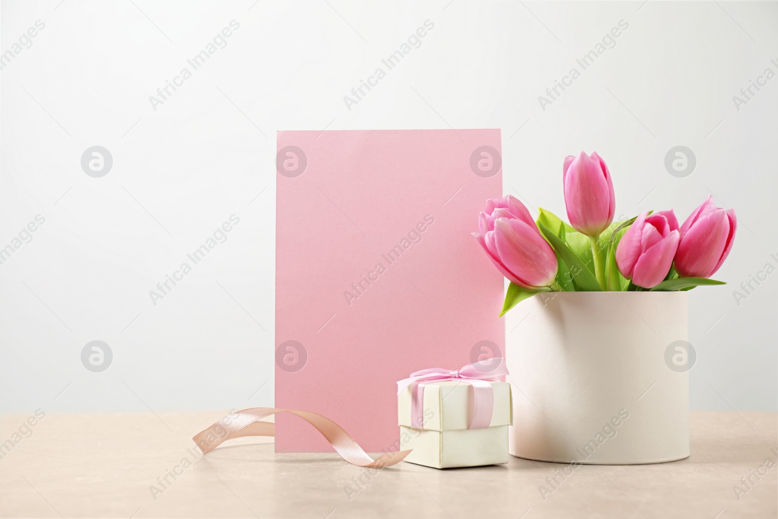 Photo of Blank greeting card, tulips and gift on table, space for text. Happy Mother's day