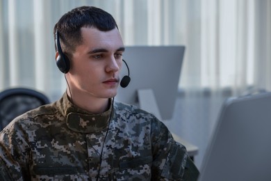 Photo of Military service. Young soldier in headphones working in office