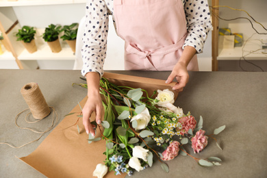 Photo of Florist making bouquet with fresh flowers at table, closeup