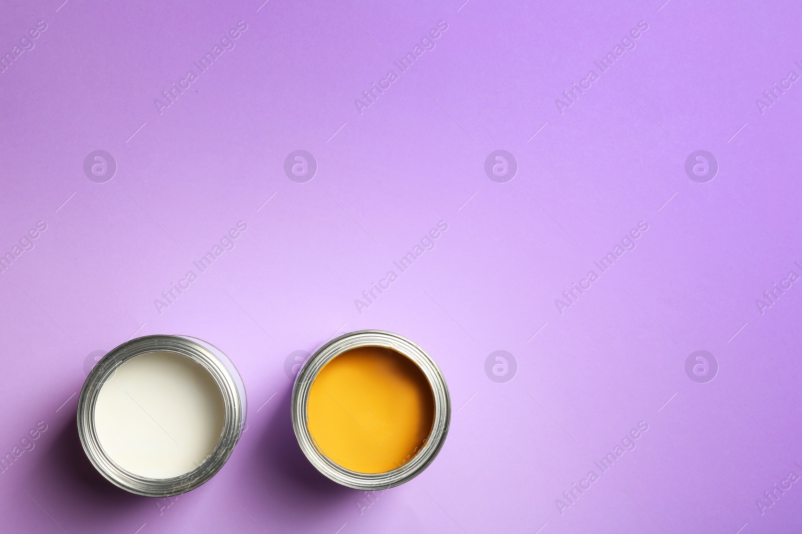 Photo of Open paint cans and space for text on color background, top view