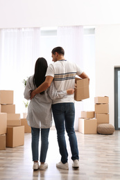 Photo of Couple in room with cardboard boxes on moving day