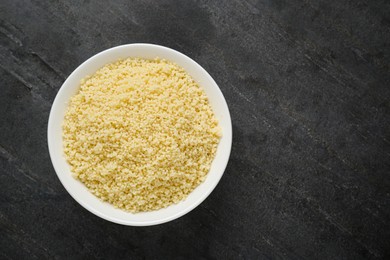 Bowl of tasty couscous on grey table, top view. Space for text
