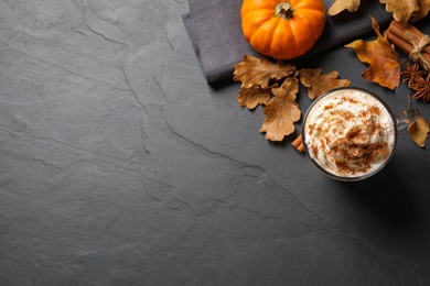Photo of Delicious pumpkin latte on black slate table, flat lay. Space for text
