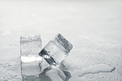 Crystal clear ice cubes with water drops on metal surface. Space for text