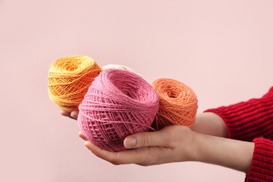 Photo of Woman holding clews of threads against color background, closeup