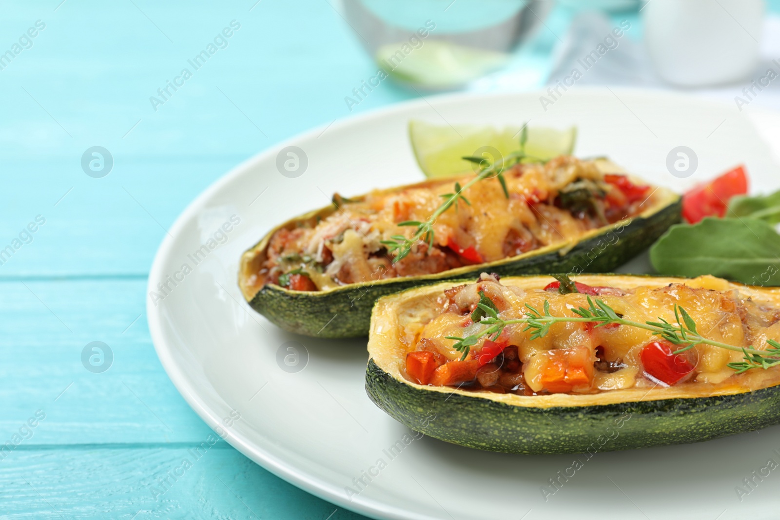 Photo of Delicious stuffed zucchini served on light blue wooden table, closeup