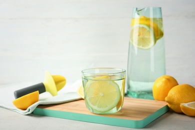 Glass of water with lemon slice on wooden board