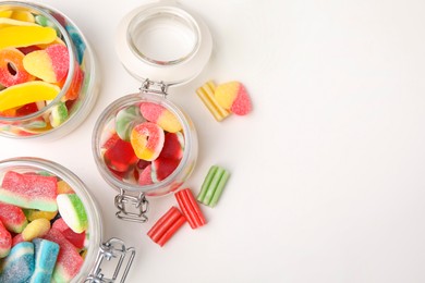 Photo of Tasty jelly candies in jars on white table, flat lay. Space for text