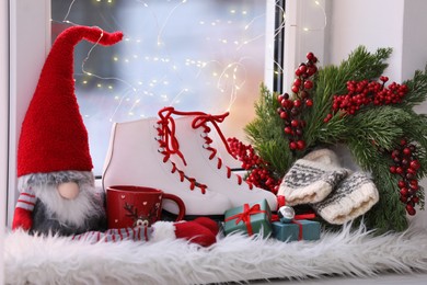 Photo of Pair of ice skates and Christmas decor on window sill indoors