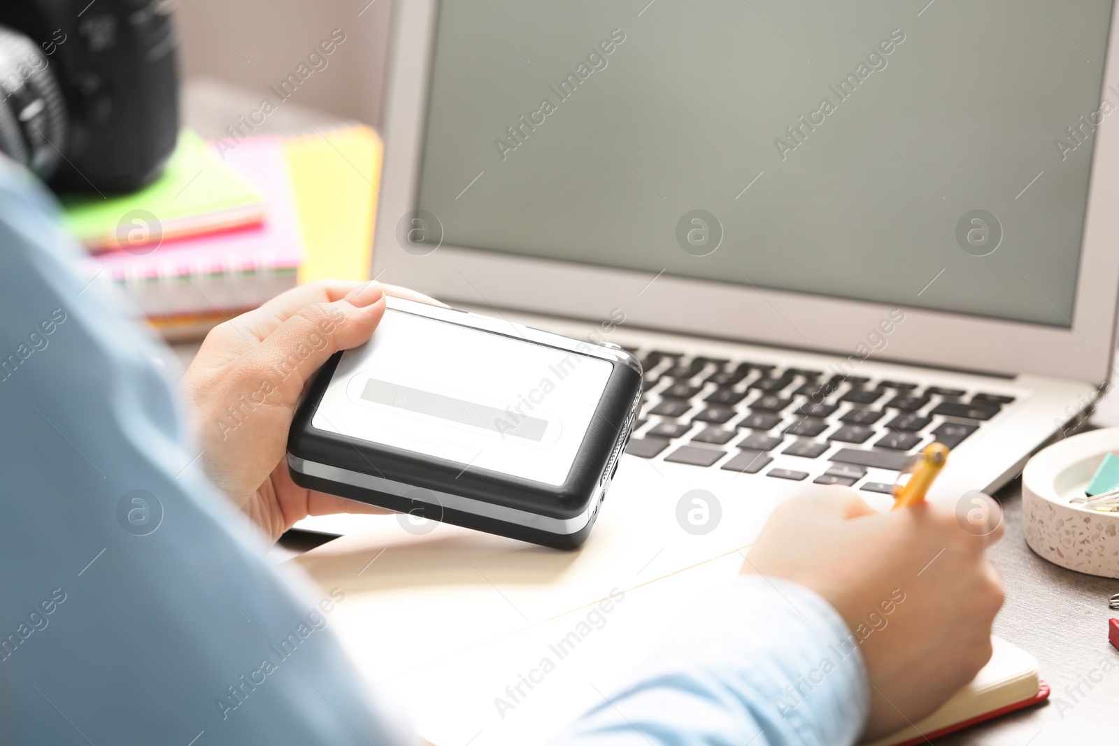 Photo of Journalist with voice recorder working at table in office, closeup