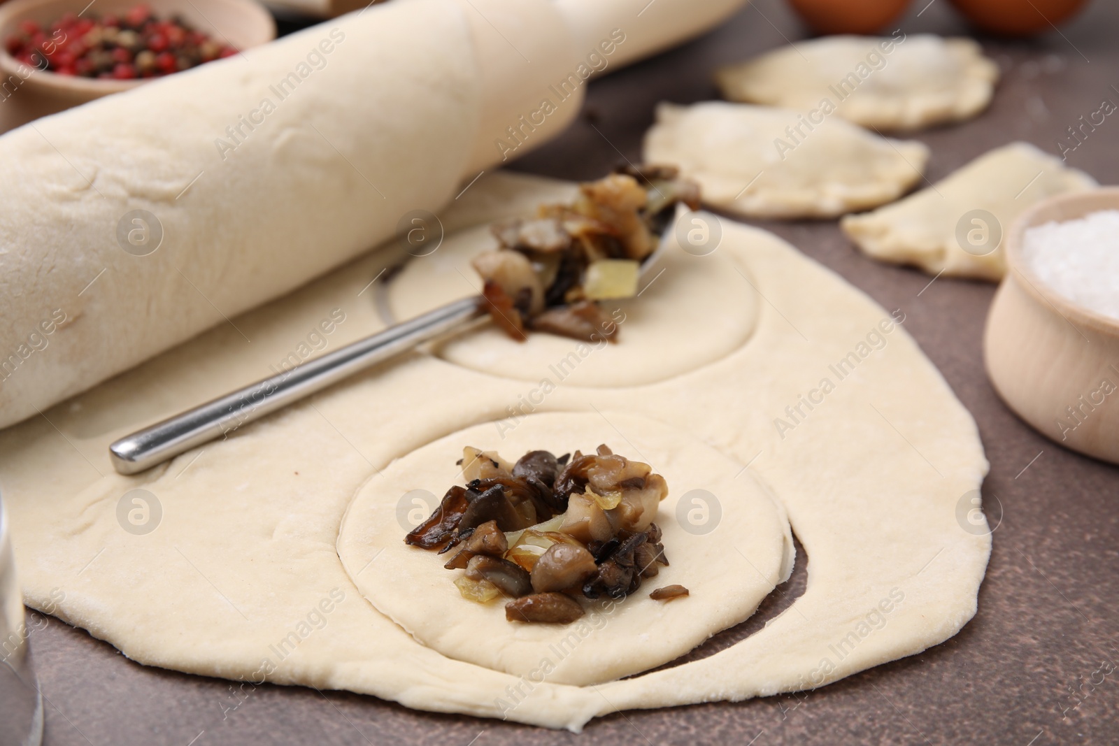 Photo of Process of making dumplings (varenyky) with mushrooms. Raw dough and ingredients on grey table, closeup