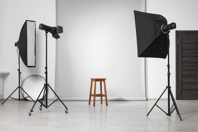 Photo of Empty stool surrounded by professional lighting equipment in photo studio