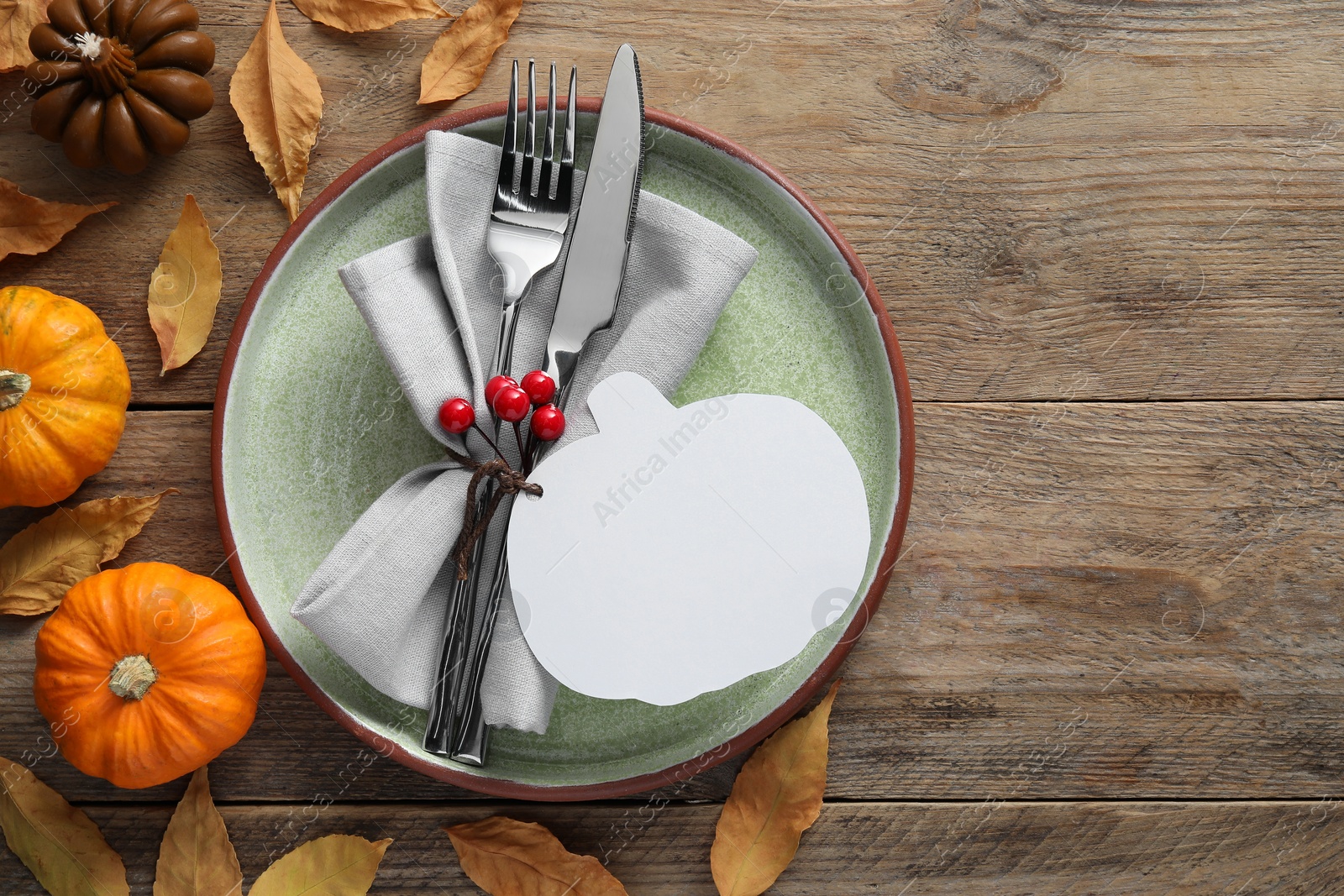 Photo of Happy Thanksgiving day. Beautiful table setting, blank pumpkin shaped card and autumn decoration on wooden background, flat lay with space for text