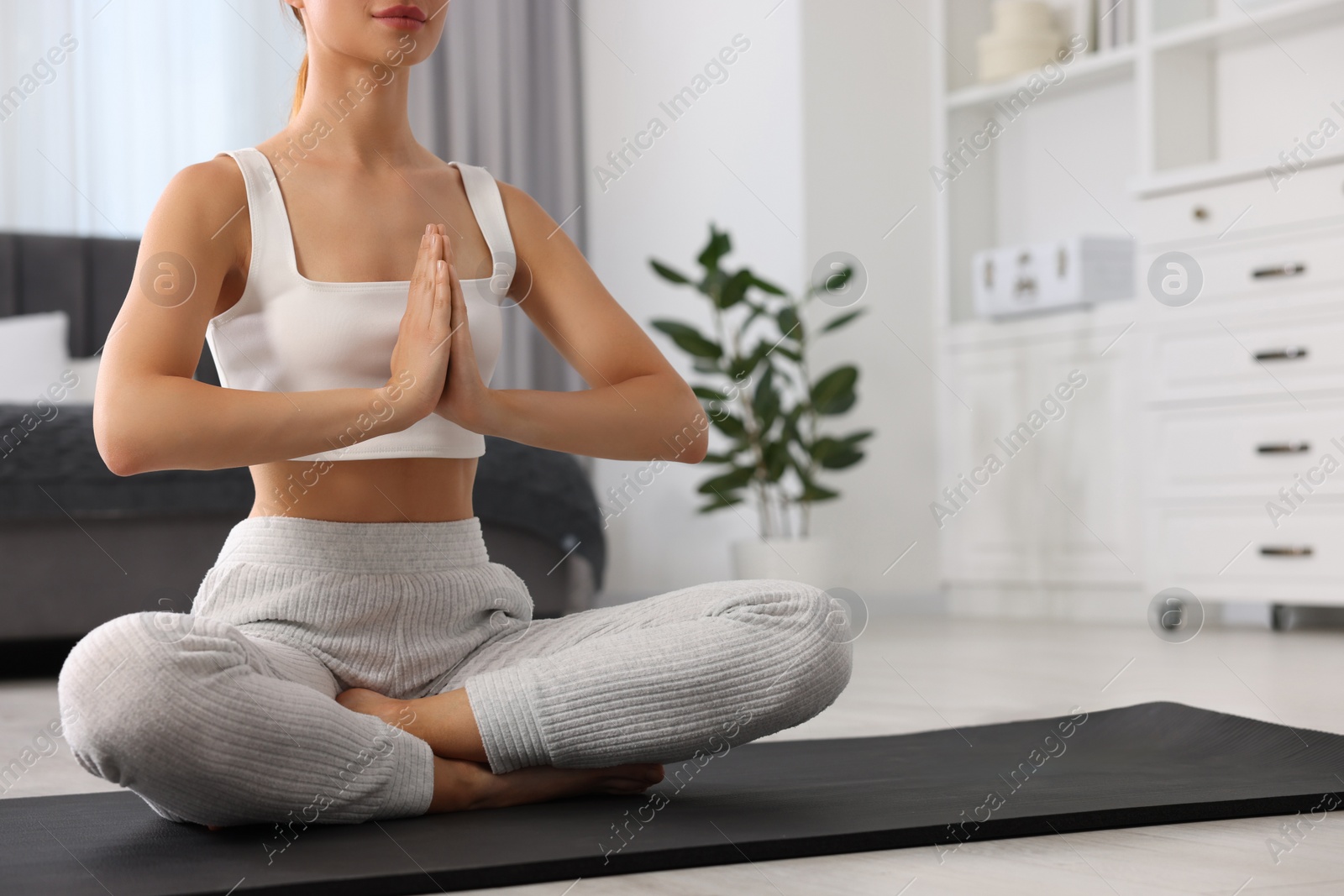 Photo of Woman practicing Padmasana on yoga mat at home, closeup and space for text. Lotus pose