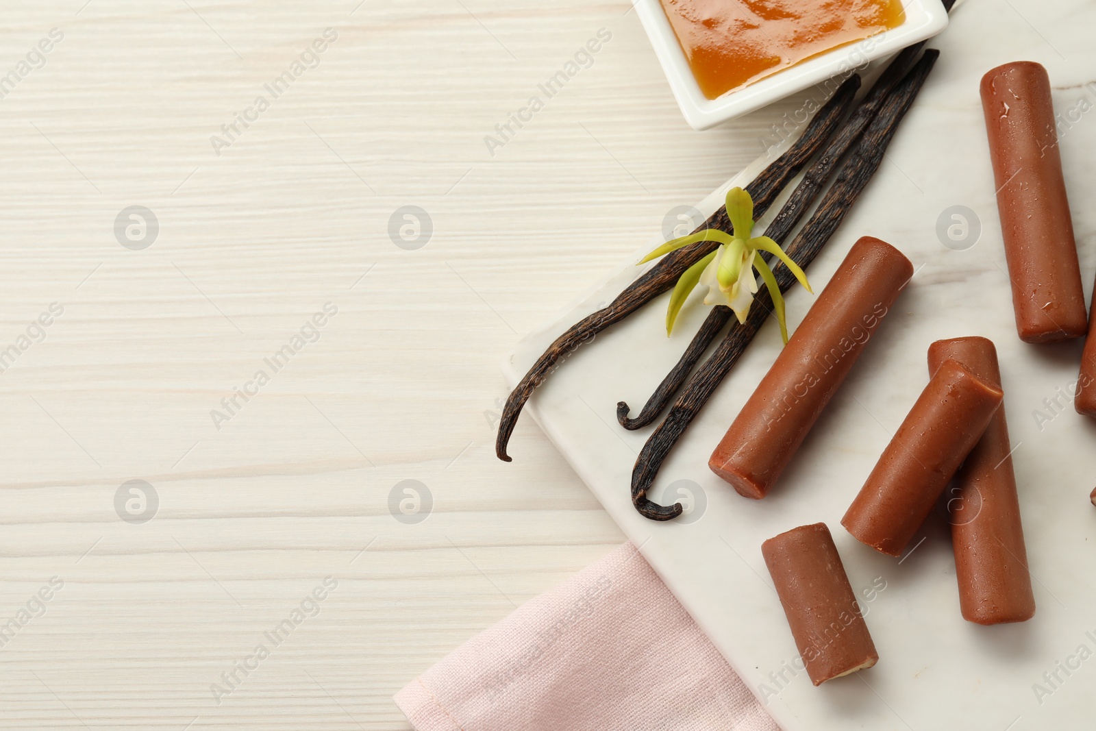 Photo of Glazed vanilla curd cheese bars served on white wooden table, flat lay. Space for text