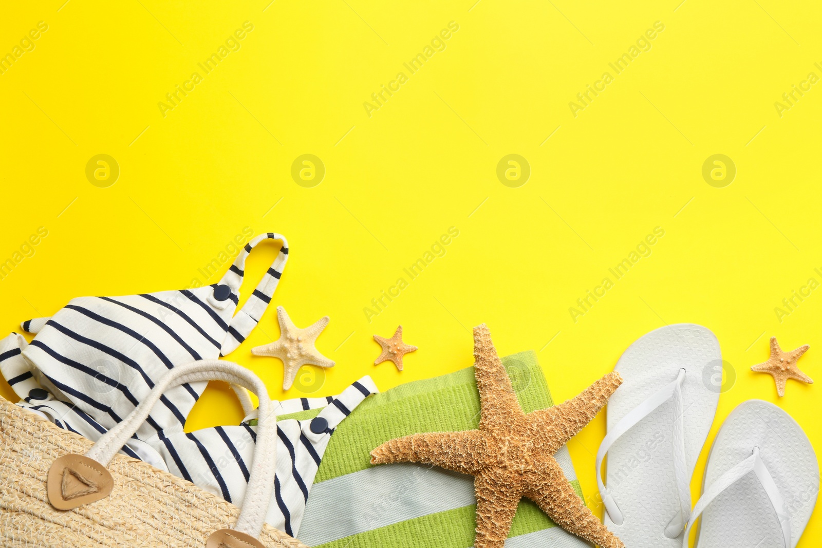 Photo of Beach accessories on yellow background, flat lay. Space for text