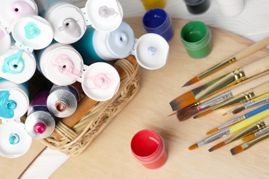 Photo of Colorful paints and brushes on table, closeup