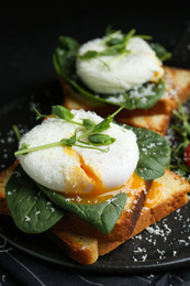 Photo of Delicious poached egg sandwiches served on slate board, closeup