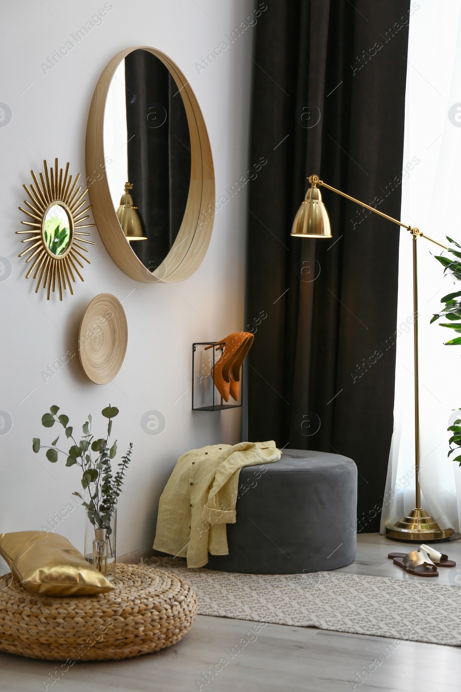 Photo of Hallway interior with big round mirror and ottoman chair near white wall