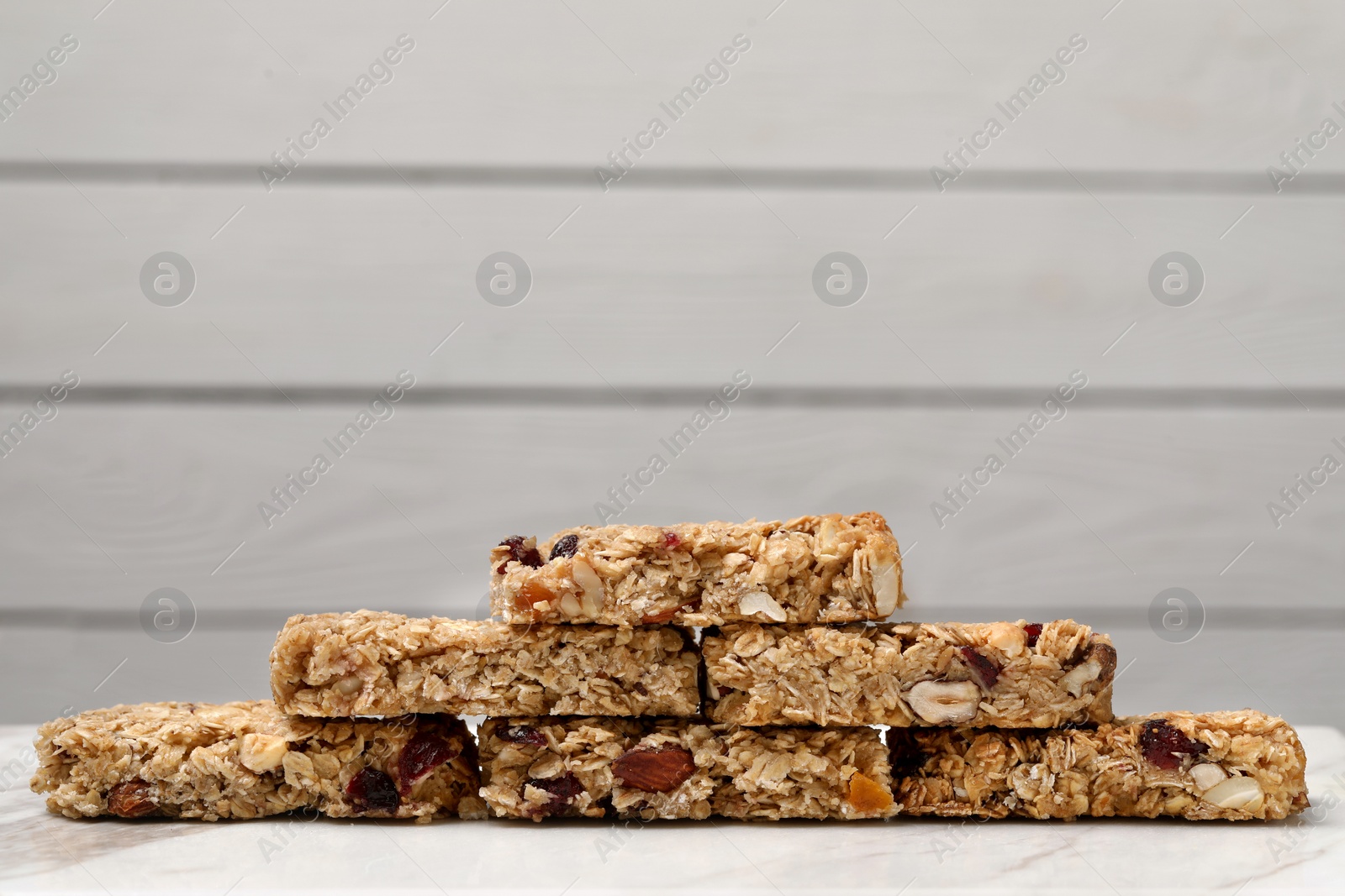 Photo of Many tasty granola bars on white table, closeup