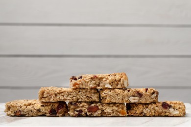 Many tasty granola bars on white table, closeup