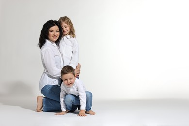 Photo of Little children with their mother on white background. Space for text