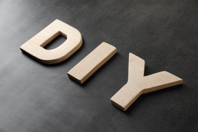 Photo of Abbreviation DIY made of wooden letters on dark background