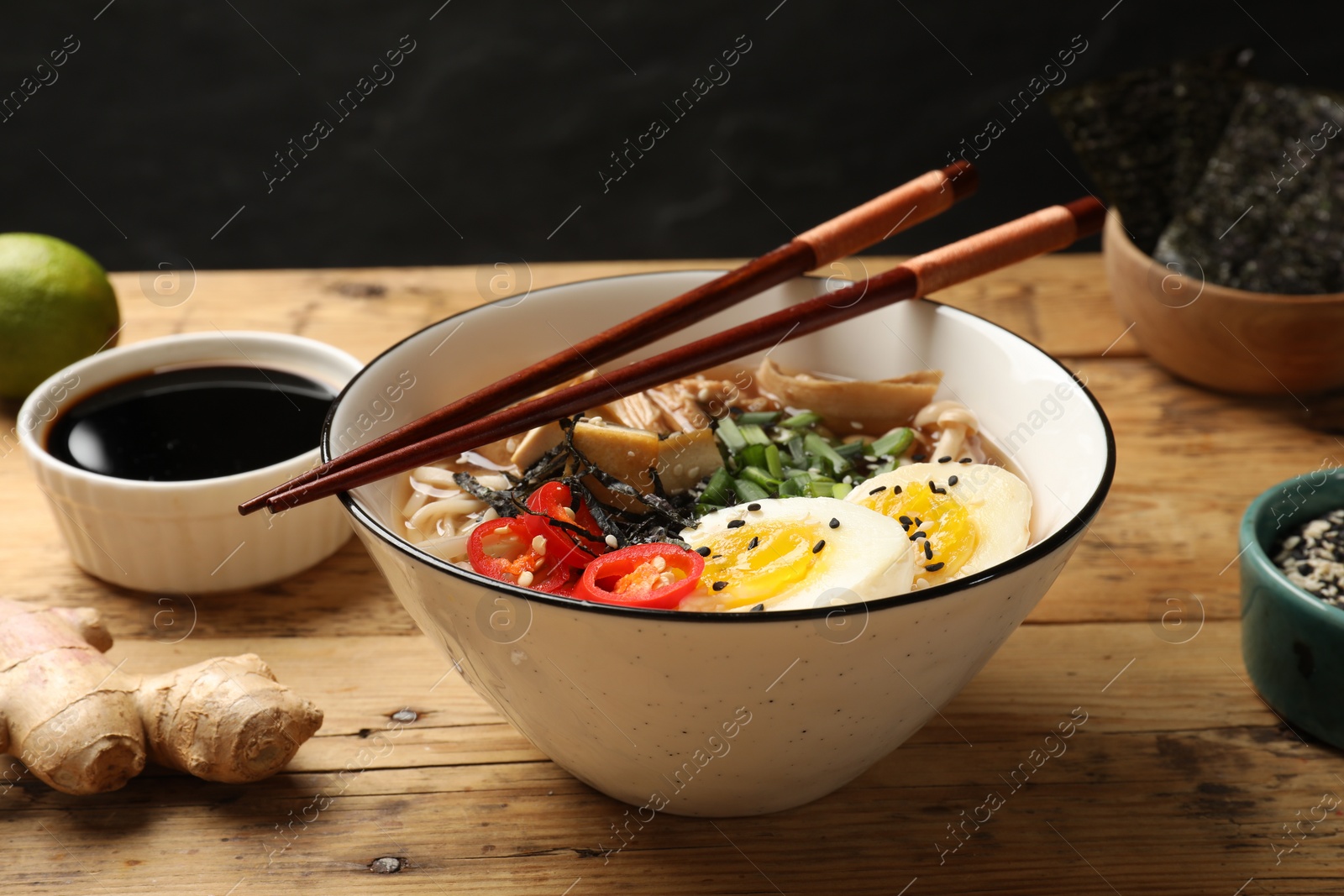 Photo of Bowl of delicious ramen and chopsticks on wooden table. Noodle soup