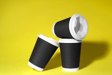 Photo of Paper cups with white lids on yellow background. Coffee to go