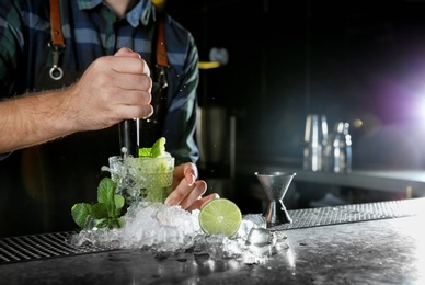 Barman making Mojito cocktail at counter in pub, closeup. Space for text