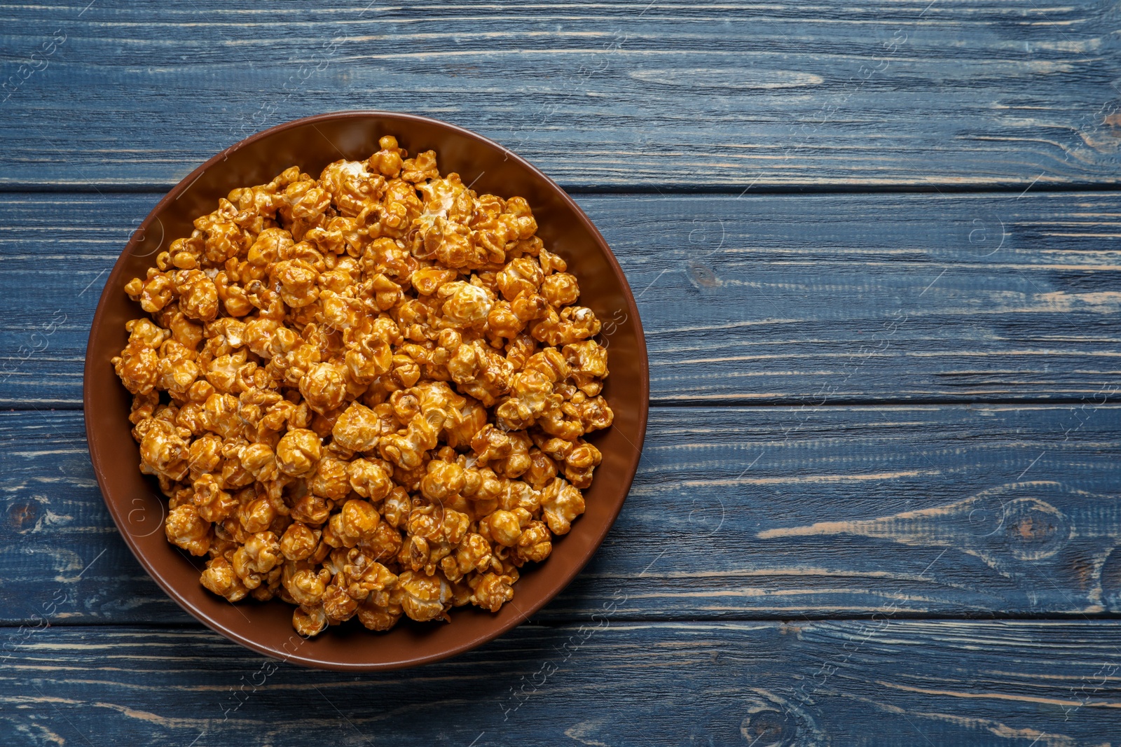 Photo of Delicious popcorn with caramel on wooden background, top view