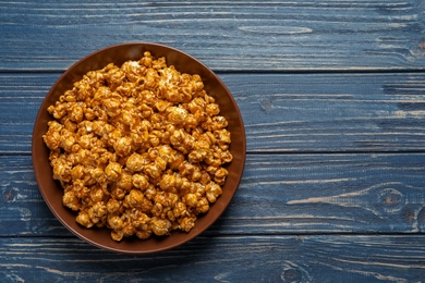 Photo of Delicious popcorn with caramel on wooden background, top view