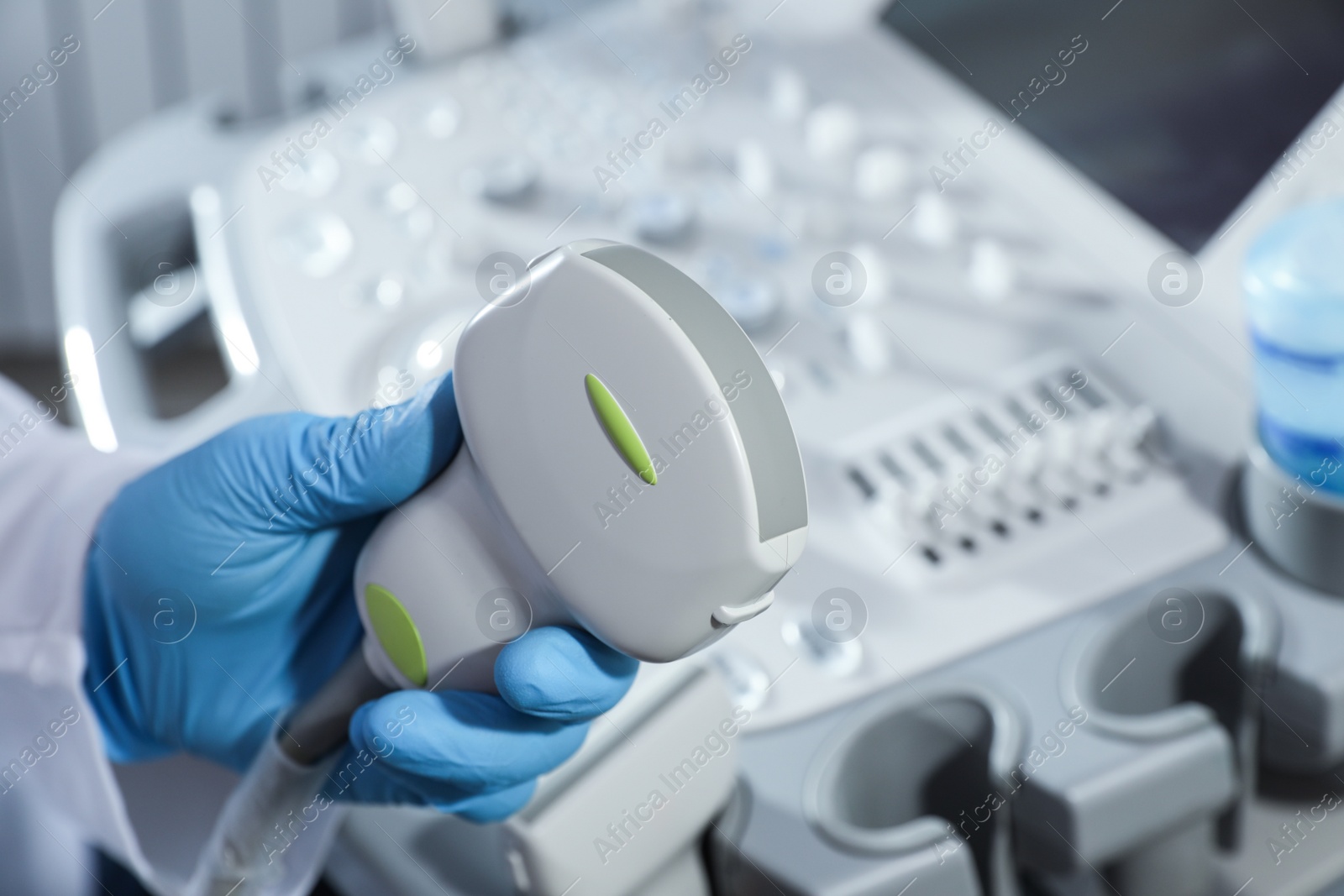 Photo of Sonographer holding ultrasound machine probe in clinic, closeup with space for text