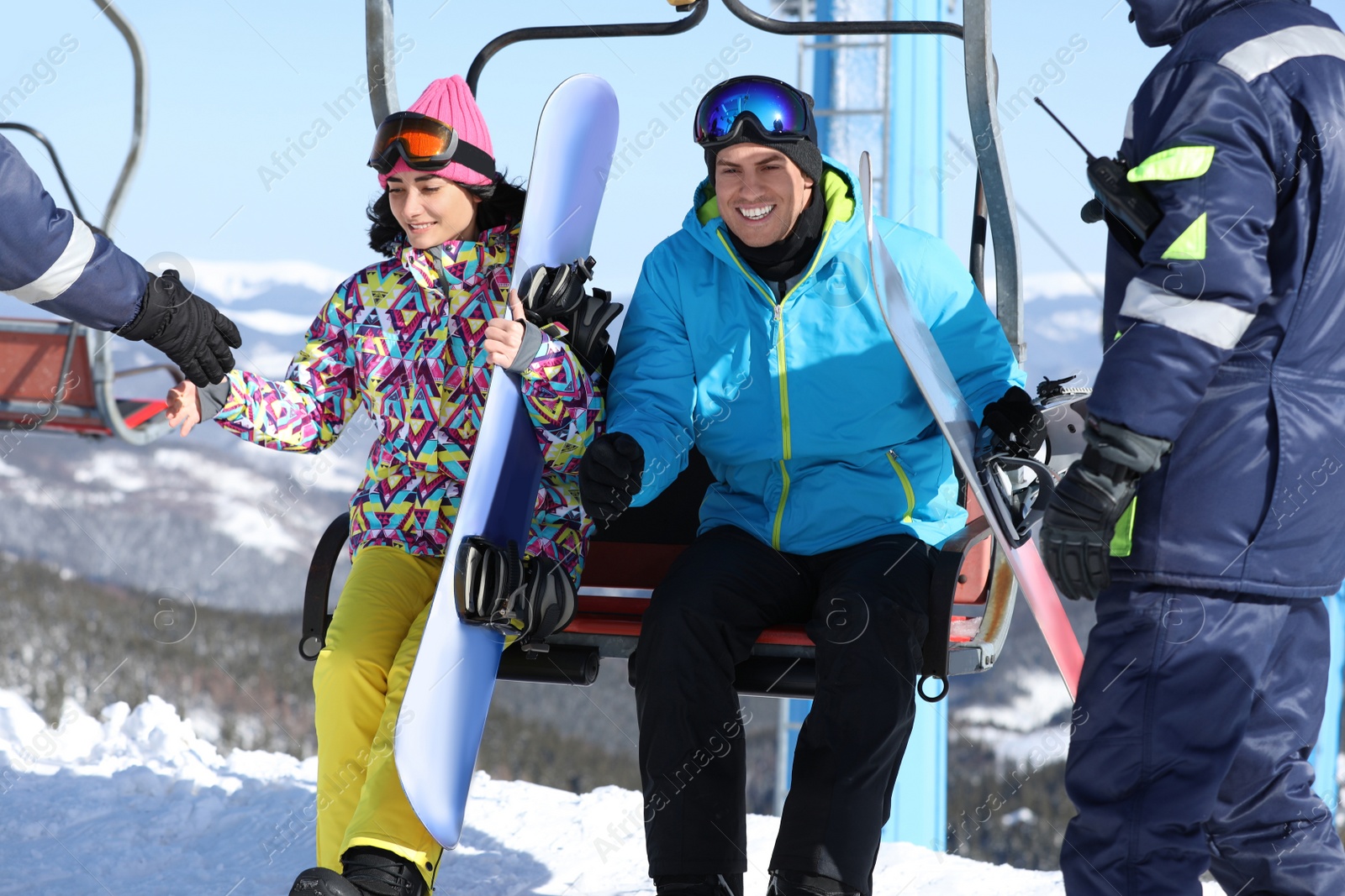 Photo of Workers helping couple get off chairlift at mountain ski resort. Winter vacation