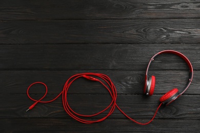 Photo of Stylish modern headphones and space for text on wooden background, top view