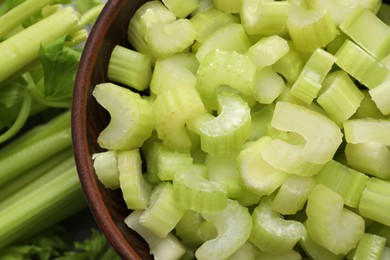 Photo of Fresh cut celery stalks in bowl and bunches, top view