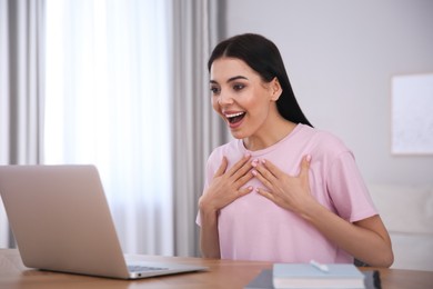 Emotional woman participating in online auction using laptop at home
