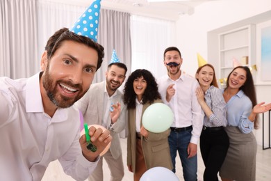 Photo of Coworkers taking selfie during office party indoors