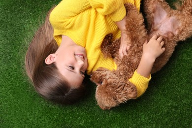 Little child with cute puppy on green grass, top view. Lovely pet