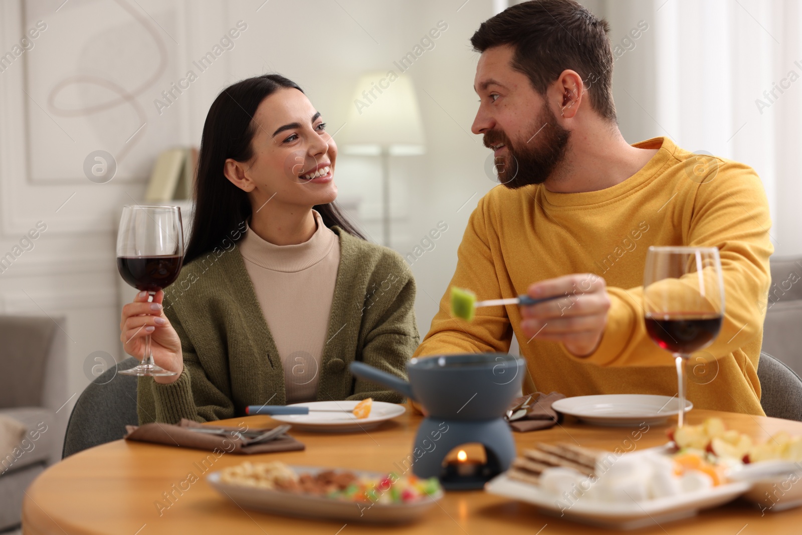 Photo of Affectionate couple enjoying fondue during romantic date at home