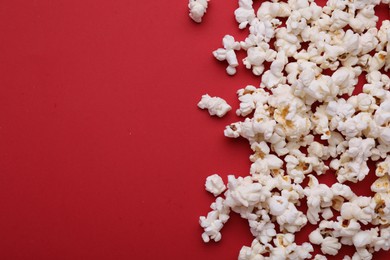 Photo of Tasty popcorn on red background, flat lay. Space for text