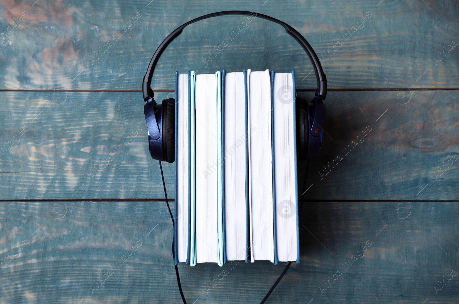 Photo of Modern headphones with hardcover books on wooden table, top view