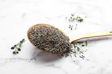 Photo of Spoon with dried and fresh thyme on white marble table, closeup