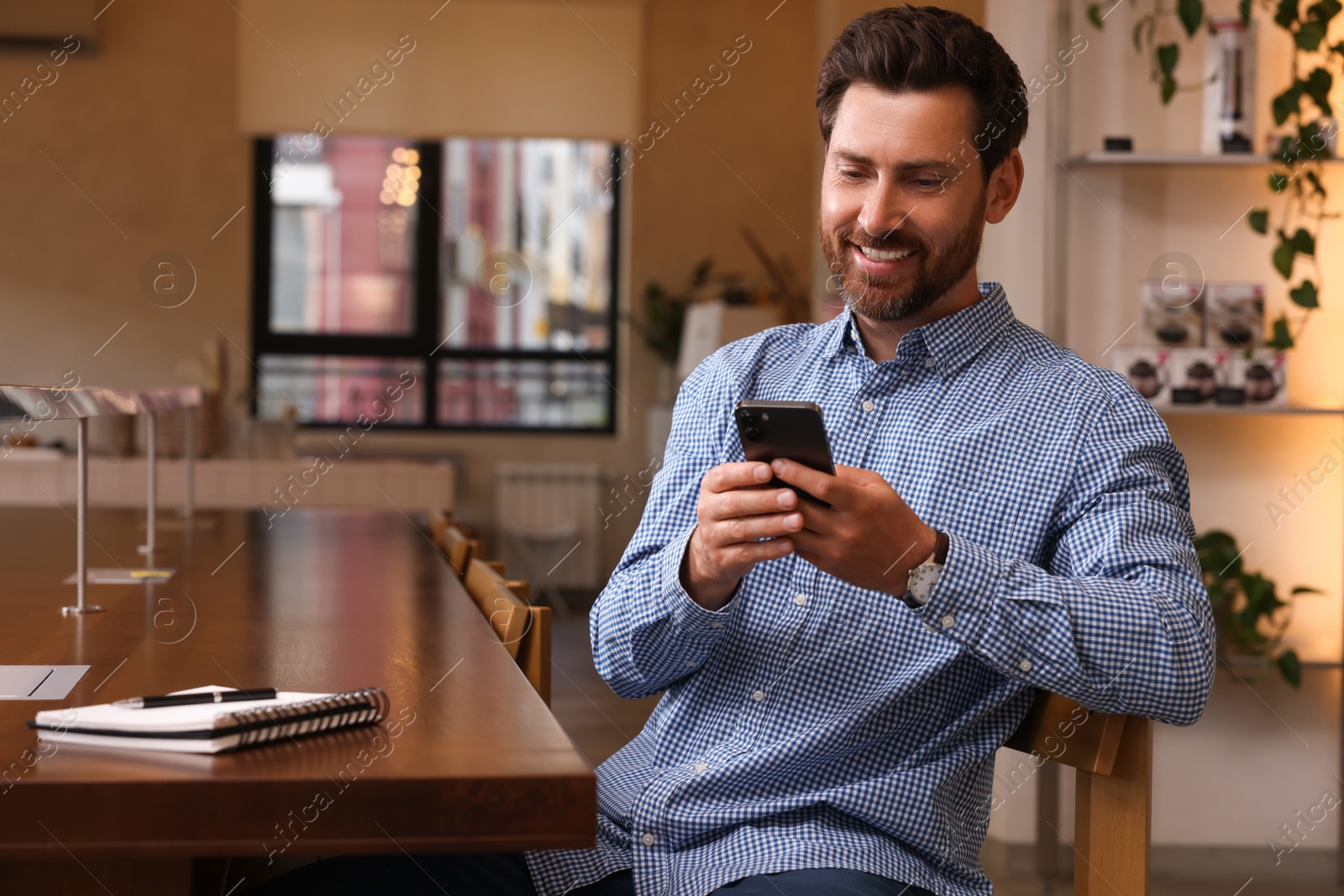 Photo of Handsome man using modern smartphone in cafe