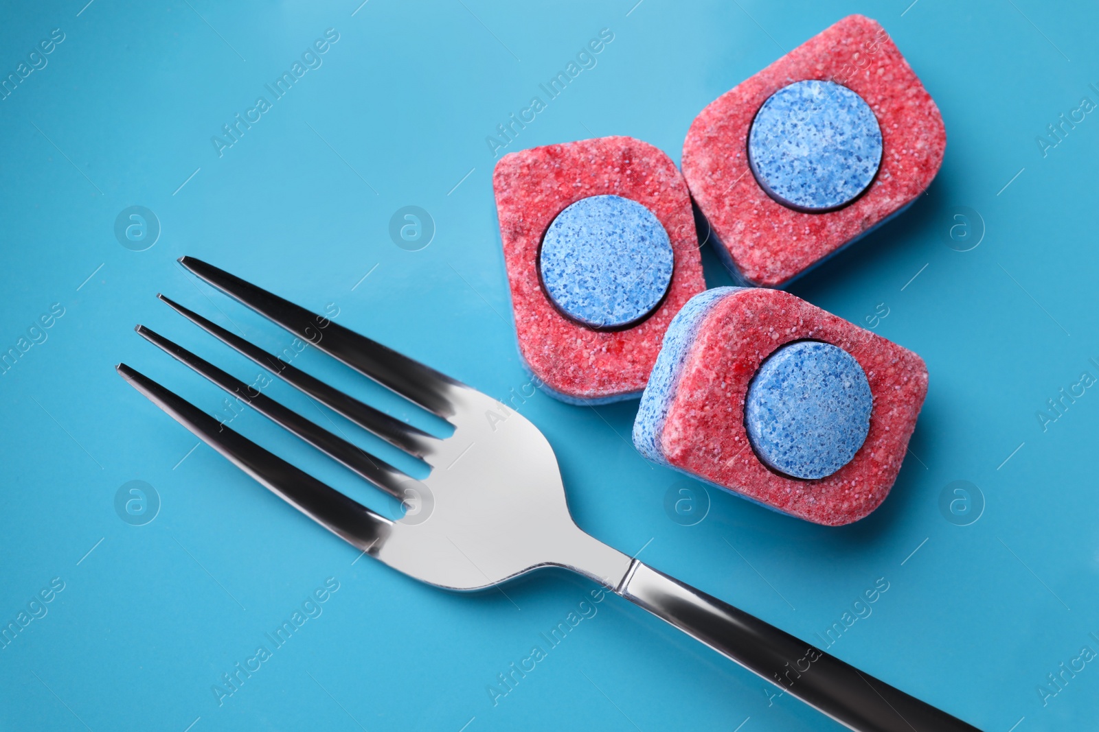 Photo of Light blue plate with fork and dishwasher detergent tablets, top view