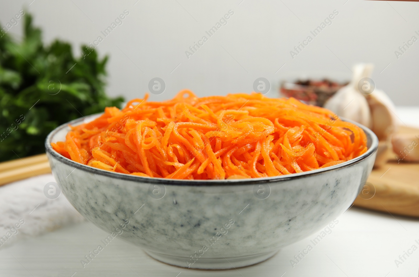 Photo of Delicious Korean carrot salad in bowl on white wooden table