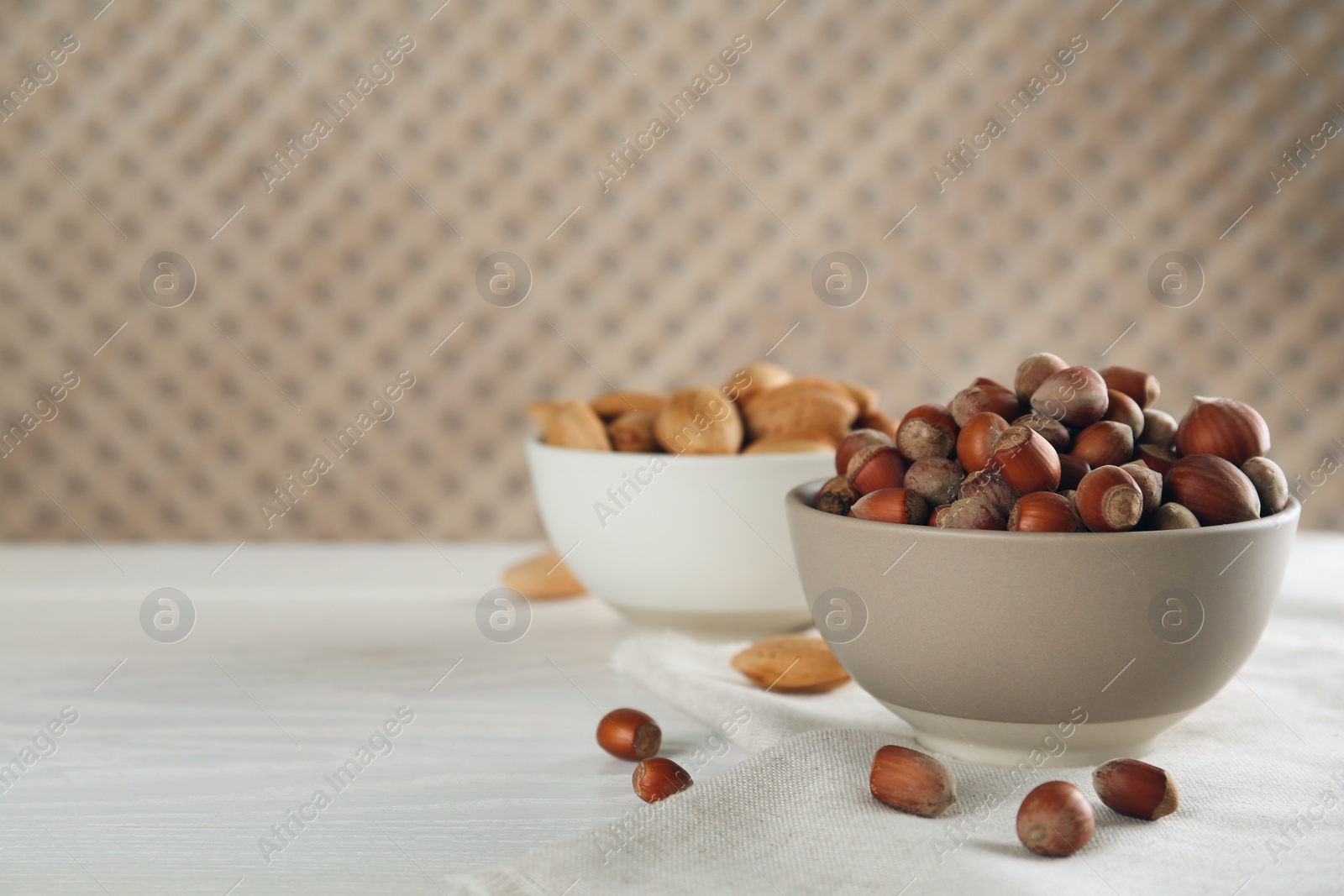 Photo of Ceramic bowl with acorns on white wooden table, space for text. Cooking utensil