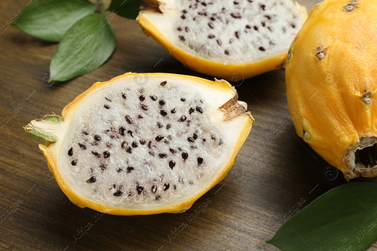 Photo of Delicious cut and whole dragon fruits (pitahaya) on wooden table